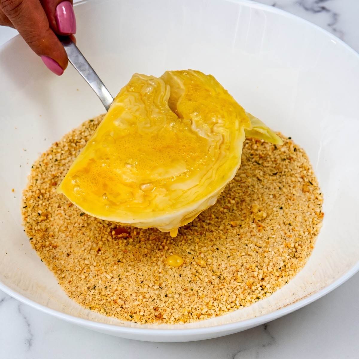 Cabbage steak coated in beaten egg before being dipped in seasoned breadcrumbs.