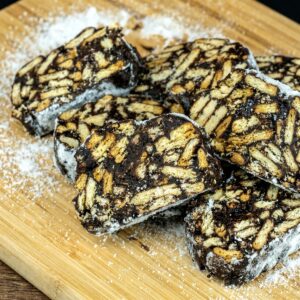No-bake chocolate salami sliced into rounds with visible cookie pieces.