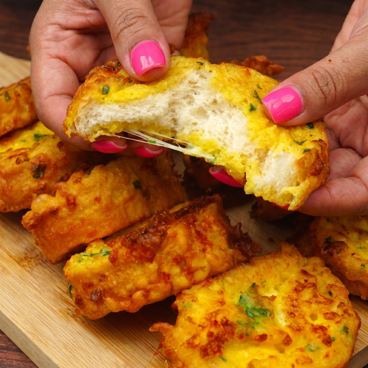 Hand holding a crispy fried bread slice with a soft cheesy center.