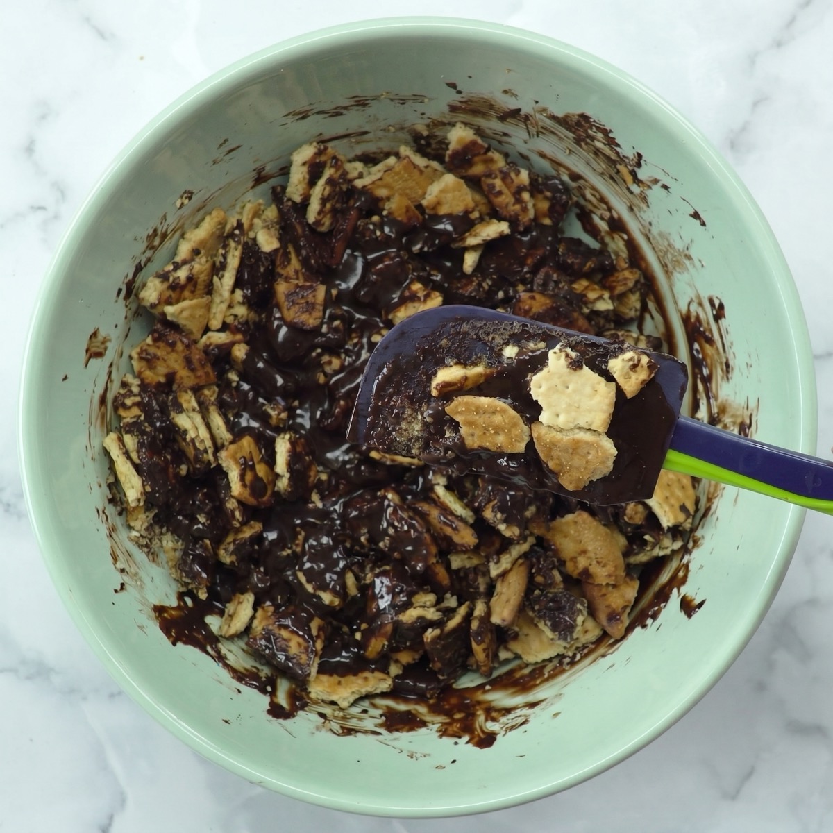 Crushed cookies mixed with chocolate base in a bowl for chocolate salami.