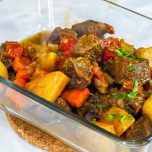 Oven-baked beef and vegetables finished in a glass baking dish with fresh parsley.