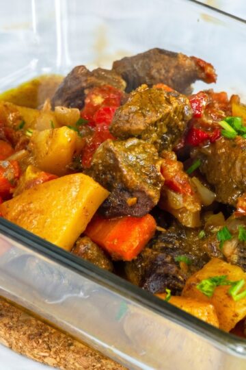 Oven-baked beef and vegetables finished in a glass baking dish with fresh parsley.