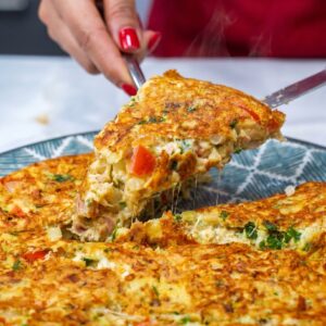 Slice of cheesy tuna omelette being lifted from a plate with melted mozzarella.