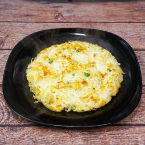 Chicken and potato omelet with eggs and grated potatoes, sprinkled with fresh herbs and served on a plate.
