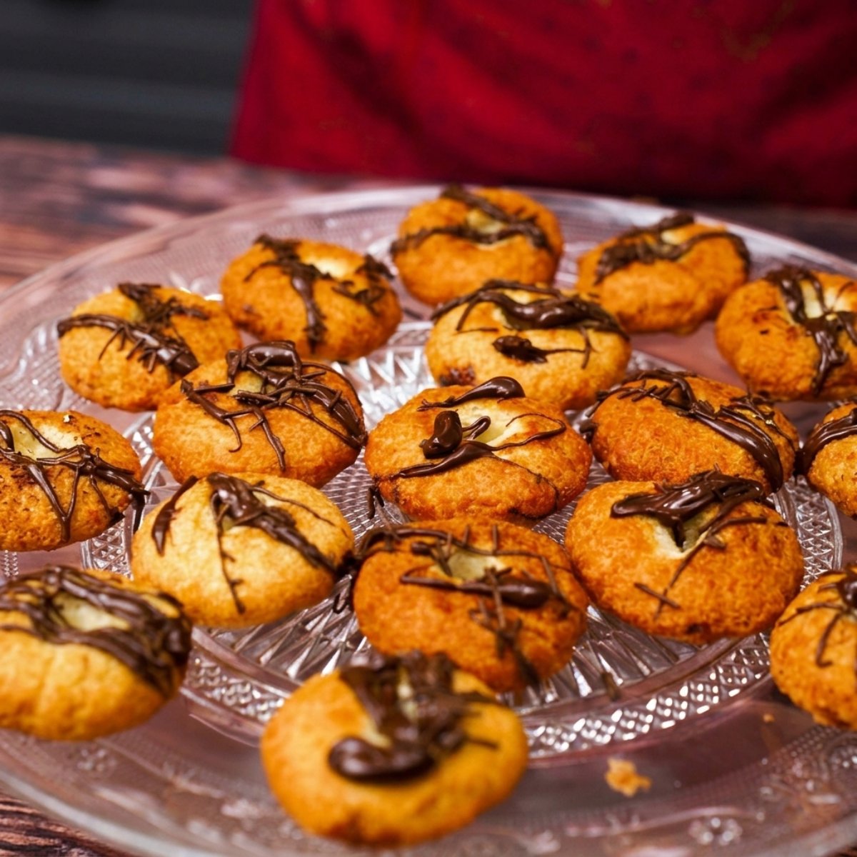 Chocolate bread donuts arranged in a glass dish with chocolate topping drizzled over them.