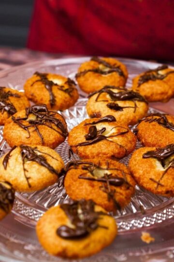Donuts di pane al cioccolato disposti in un vassoio di vetro, con copertura di cioccolato colata sopra.