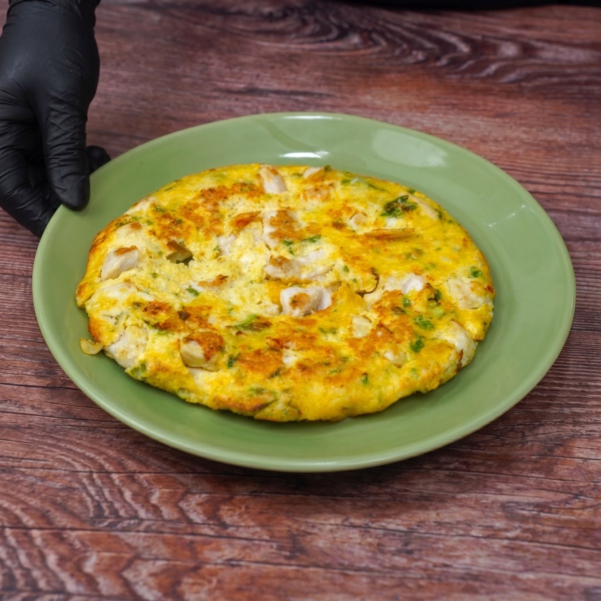 Fertiges Hähnchen mit Eiern aus der Pfanne auf einem Teller serviert.