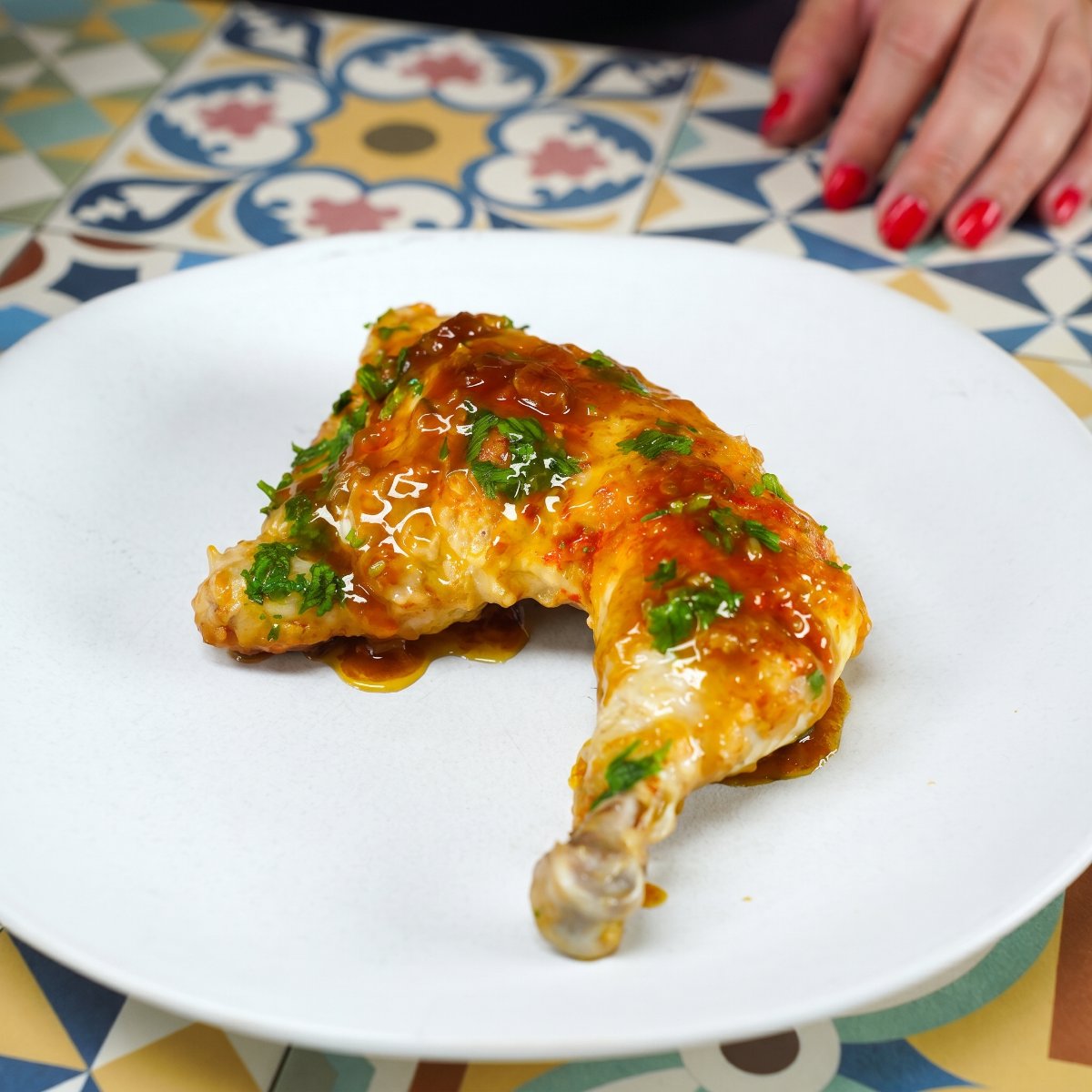 Golden chicken drumstick coated in glossy sauce and sprinkled with chopped herbs.