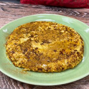 Bananen-Haferflocken-Pfannkuchen mit Zimt bestreut und mit etwas Honig beträufelt, auf einem Teller serviert.