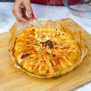 Freshly baked rustic puff pastry apple tart, still steaming, on a wooden board.