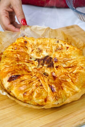 Freshly baked rustic puff pastry apple tart, still steaming, on a wooden board.
